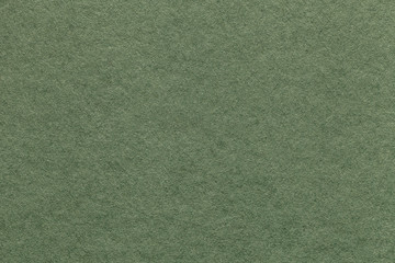 Texture of old light green paper background, closeup. Structure of dense olive cardboard