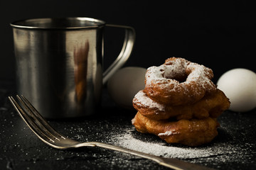 Freshly baked doughnuts eggs and flour dark background