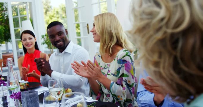 Friends applauding woman while having meal