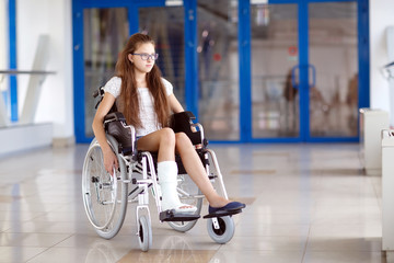 A young girl in a wheelchair is standing in the corridor of the hospital.