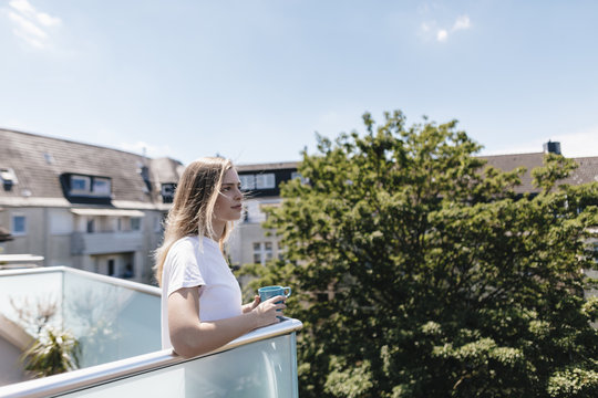 Young woman on a balcony, drinking tea
