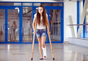 A young girl is on crutches in the corridor of the hospital.