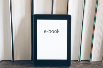 e-book reader on a stack of books on rustic wooden table concept