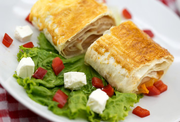 Lavash rolls with meet, vegetables and cheese served with green lettuce salad, feta chesse and red pepper on rustic wooden table. Healthy breakfast concept