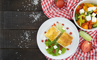 Lavash rolls with meet, vegetables and cheese served with green lettuce salad, feta chesse and red pepper on rustic wooden table. Healthy breakfast concept. Top wiev