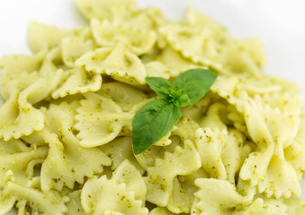  Farfalle pasta with pesto genovese (basil sauce) on rustic wooden table. Italian cuisine