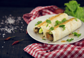 Lavash rolls with meat, vegetables and cheese served with green lettuce salad on rustic wooden table. Healthy breakfast concept. Greek traditional food - Gyro