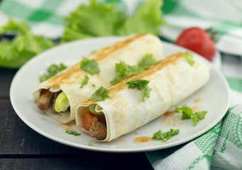 Lavash rolls with meat, vegetables and cheese served with green lettuce salad on rustic wooden table. Healthy breakfast concept. Greek traditional food - Gyro