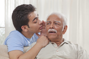 Grandson whispering into grandfather's ear