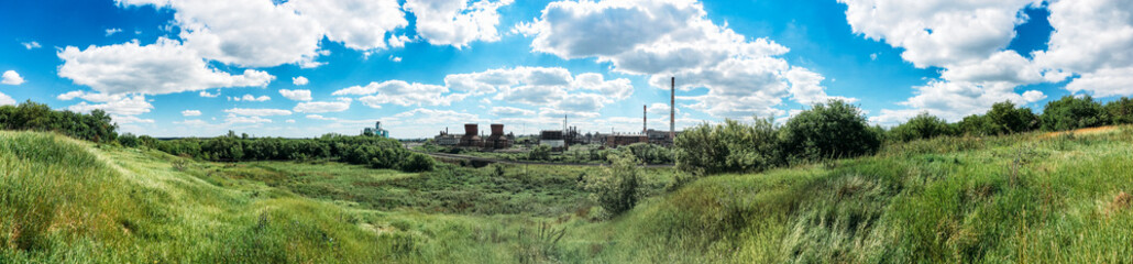 Fototapeta na wymiar Panorama of green hills and industrial plant with chimneys 