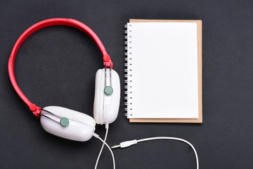 Headphones in white and red color with empty notebook