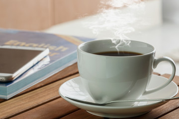 Coffee espresso cup hot  on a hardwood table,With book and  smart phone