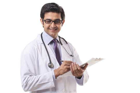 Happy male doctor writing on clipboard over white background 