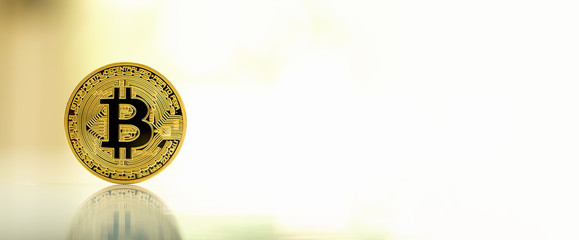 Gold bitcoin cryptocurrency on reflective table with bright background