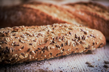 Macro view of fresh crunchy baguette bread with different seeds on the rustic wooden desk