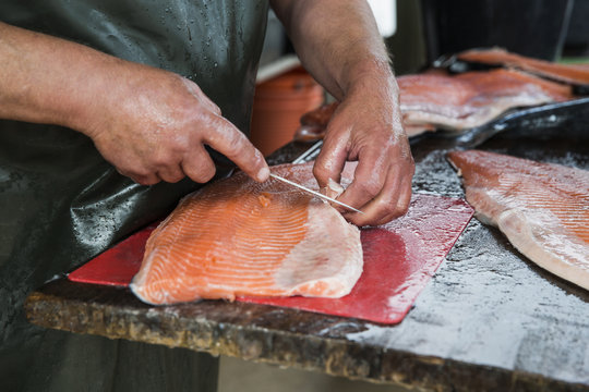 Fishmonger preparing fillets from whole salmon