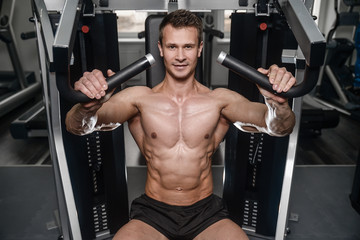 Naklejka premium Caucasian handsome fitness model training in the gym. Man on diet flexing muscles