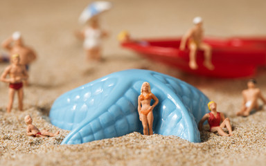 miniature people in swimsuit on the beach