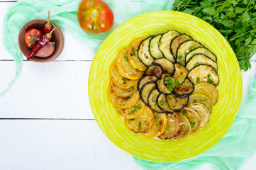 Fried circles of zucchini, eggplant on a plate on a white background. Top view. Vegetarian cuisine.