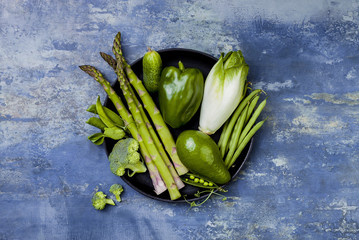 Green veggies group on a tray. Vegetarian dinner ingredients. Green vegetables variety. Overhead,...