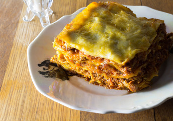 Plate of single serving of spicy beef lasagne for supper on rustic wooden table