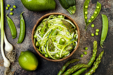 Obraz premium Zucchini spaghetti or noodles (zoodles) bowl with green veggies. Top view, overhead