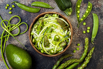 Zucchini spaghetti or noodles (zoodles) bowl with green veggies and garlic scape pesto. Top view,...