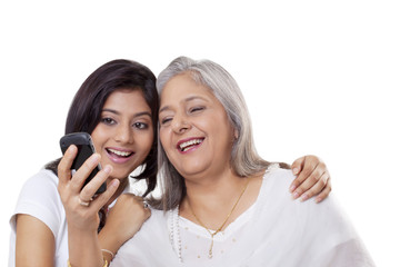 Mature woman and her granddaughter looking at a mobile phone 