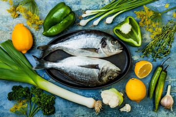 Dorado in baking form ready to cooking, preparation on rustic blue background with fresh...