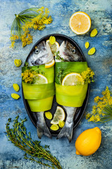 Dorado wrapped in leek in baking form ready to cooking, preparation on rustic blue background with...