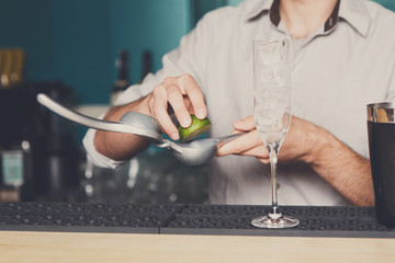 Bartender making cocktail with lime, close-up