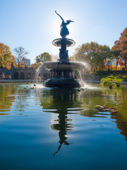 Bethesda Fountain against sun with angel statue reflecting in the water, Central Park, New York, USA