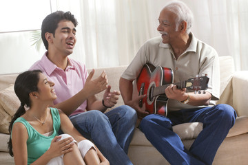 Grandfather playing the guitar and grandchildren singing
