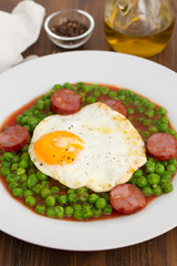 peas with smoked sausage and fried egg on plate