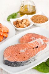 raw salmon, shrimps, nuts and olive oil on wooden background