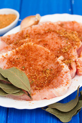 raw pork with herbs on white dish on wooden background
