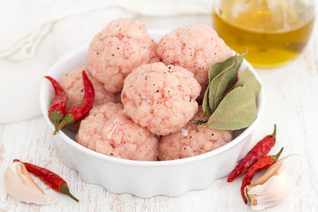 raw pork meatballs on dish on wooden background