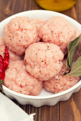 raw pork meatballs on dish on wooden background