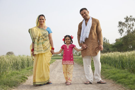 Full length portrait of a young girl with her family walking on rural road 