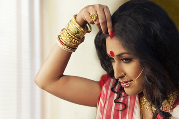 Bengali woman putting sindoor on her forehead