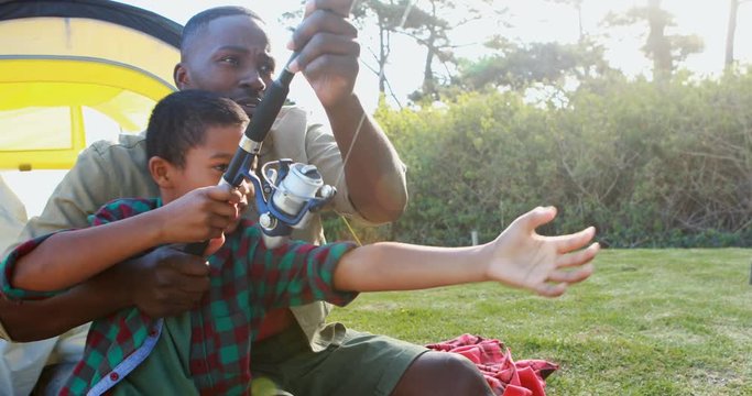 African American man father teaching boy son how to catch a fish