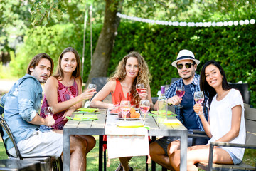 group of friends having fun picnic lunch party outdoor in backyard during summer holiday vacation