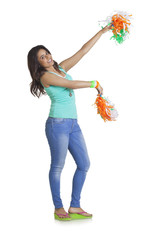 Full length portrait of happy young female holding Indian pom poms tricolor over white background 