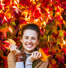Portrait of smiling young woman in front of autumn foliage