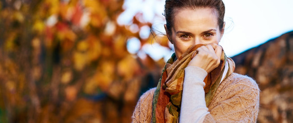 Young woman hiding in scarf in autumn evening