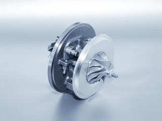 Turbocharger on metallic background. Car turbine - part of engine. Blue toned.