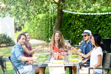group of friends having fun picnic lunch party outdoor in backyard during summer holiday vacation