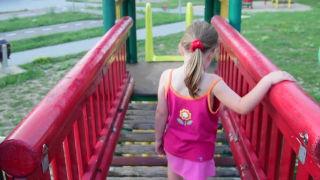 View of girl goes on rope bridge in the playset at playground