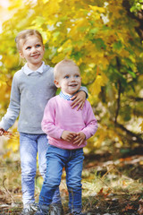 Fototapeta premium Cheerful little brother and sister standing in the park in autumn