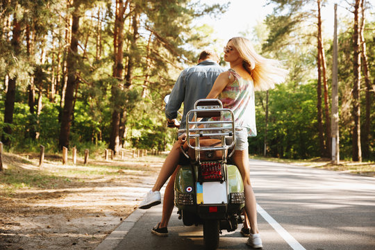 Back view image of young man on scooter with girlfriend.